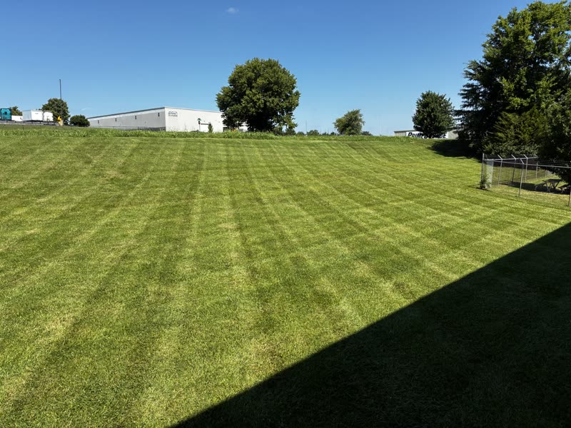 Commercial lawn in front of a white warehouse and picnic table.